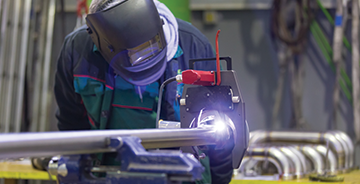 Skilled welder using a welding torch to fabricate stainless steel piping